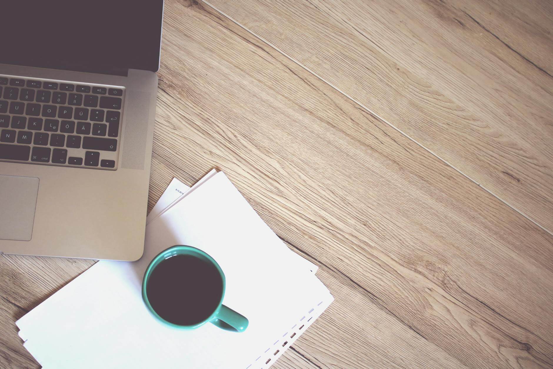 gray laptop computer beside green ceramic mug